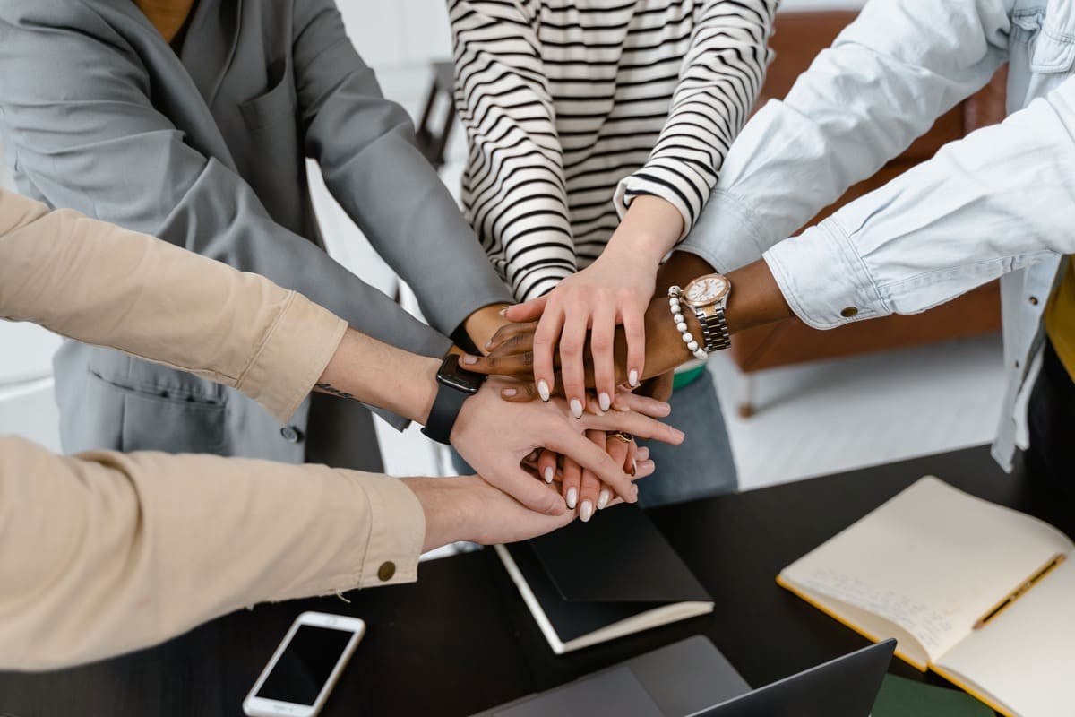 Mains de plusieurs personnes empilées en signe de collaboration.