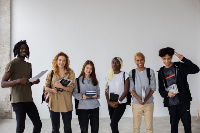 Un groupe de six étudiants debout, souriant, tenant des livres et cahiers.