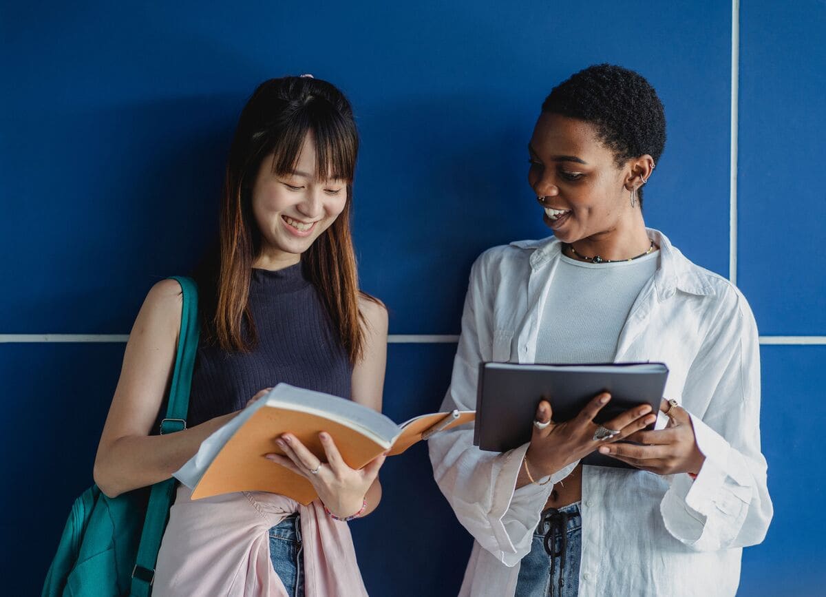 Deux personnes souriantes lisant des documents devant un mur bleu.