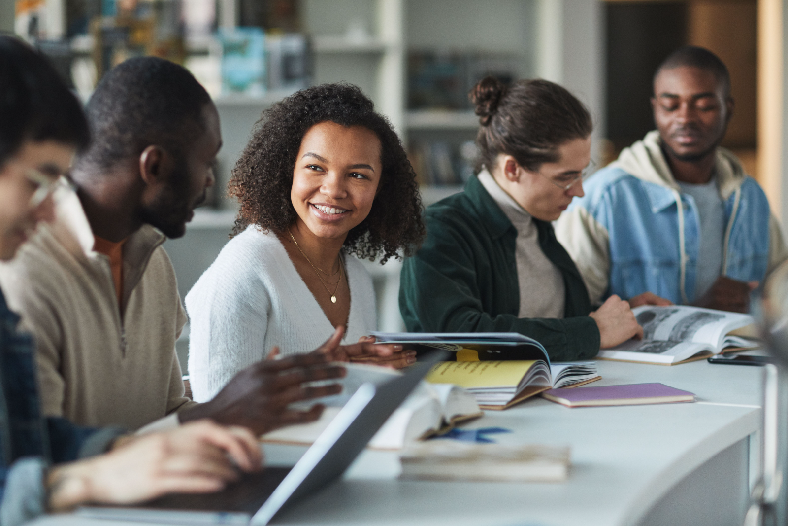 Un groupe d'étudiants souriants discutant et étudiant ensemble à une table.